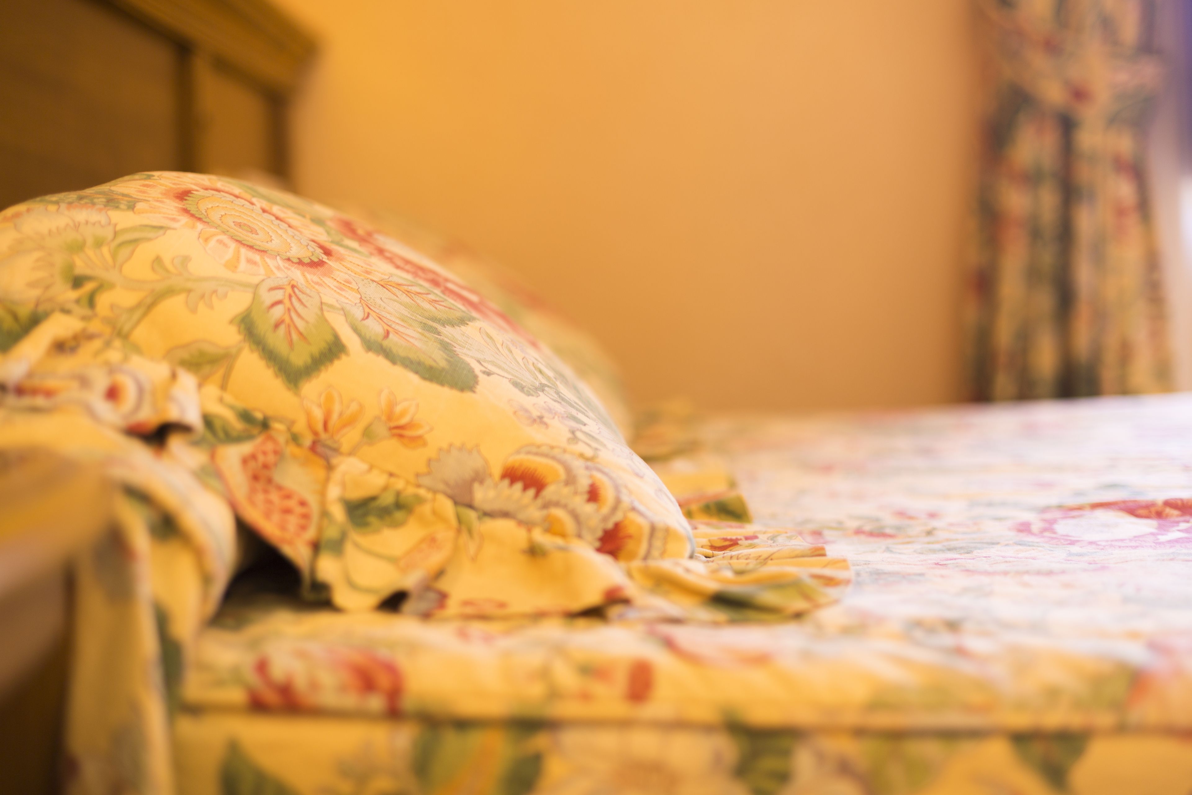 A bed with a floral-patterned bedspread and a pillow.