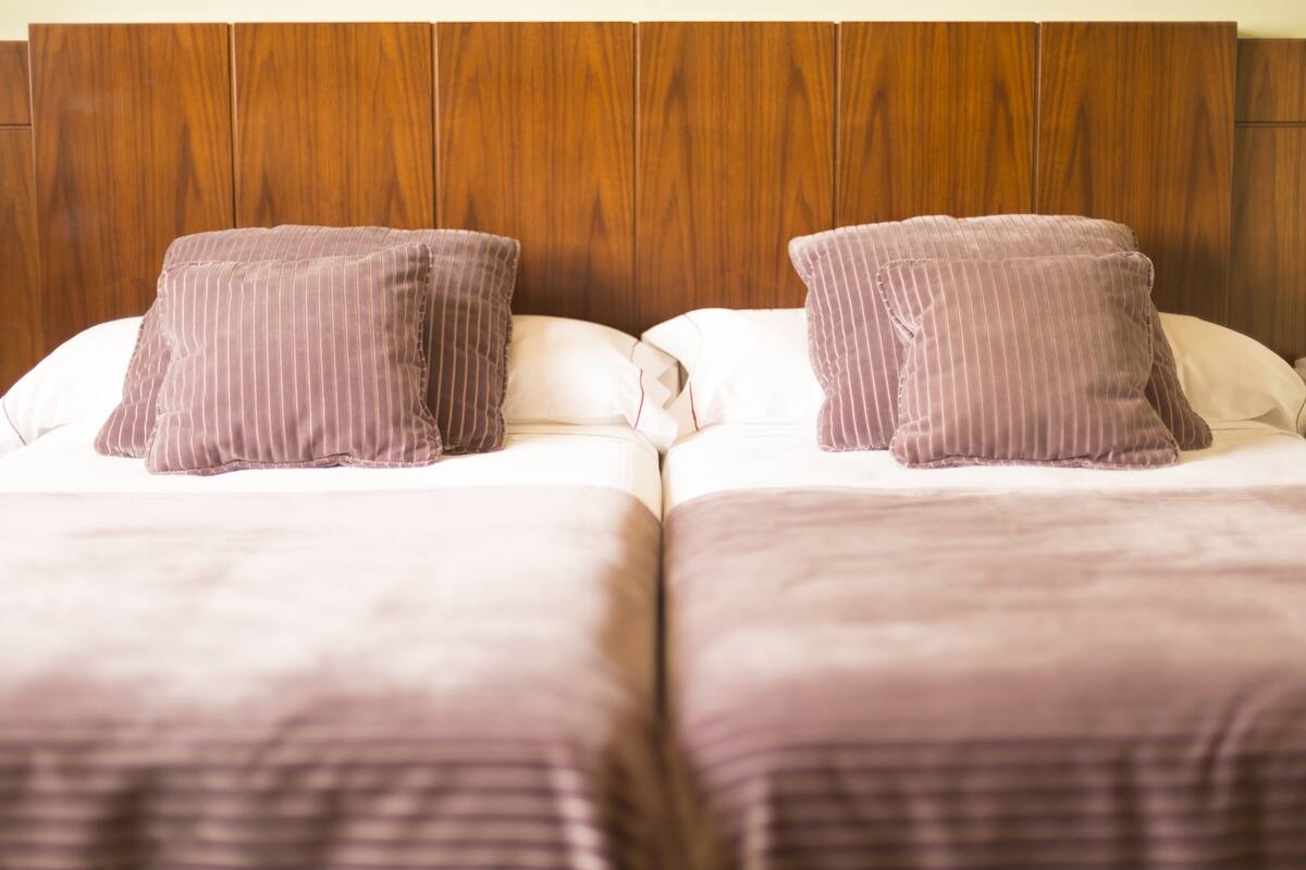 Ein Doppelbett mit hölzernem Kopfteil und zwei Kissen.