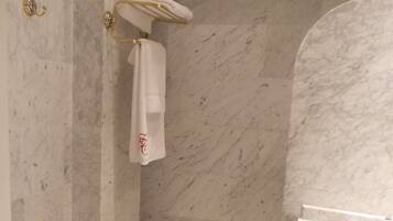 A bathroom with a marble floor, a bathtub, a sink, and a towel rack.