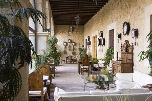 A cozy, rustic interior with wooden furniture, a glass coffee table, and various plants.