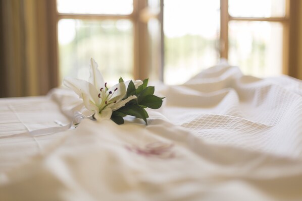 A bed with a white floral arrangement and a lace cover.