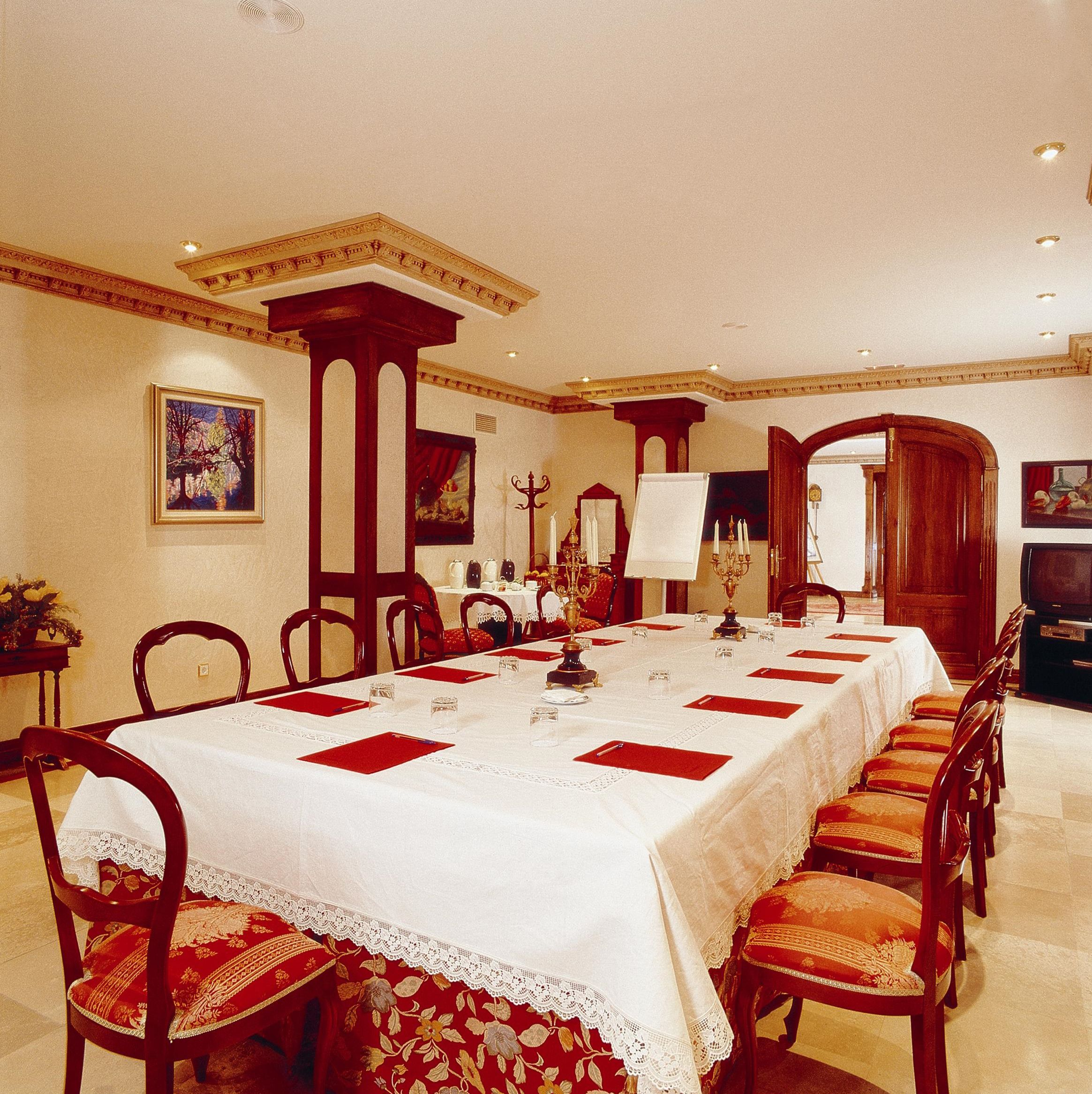 Un comedor formal con una larga mesa dispuesta para una comida, rodeada de sillas.