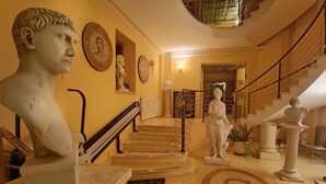 A grand staircase with classical statues and a bust on the wall. - Hotel Seccy Boutique Art & Museum (Fiumicino)