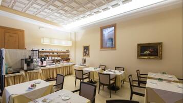 Un'area pranzo con tavoli apparecchiati, un angolo cottura e un soffitto con motivo a griglia.