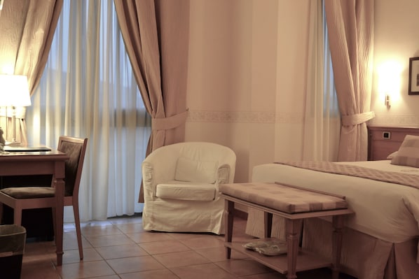 A hotel room with a bed, a chair, a desk, and a lamp.
