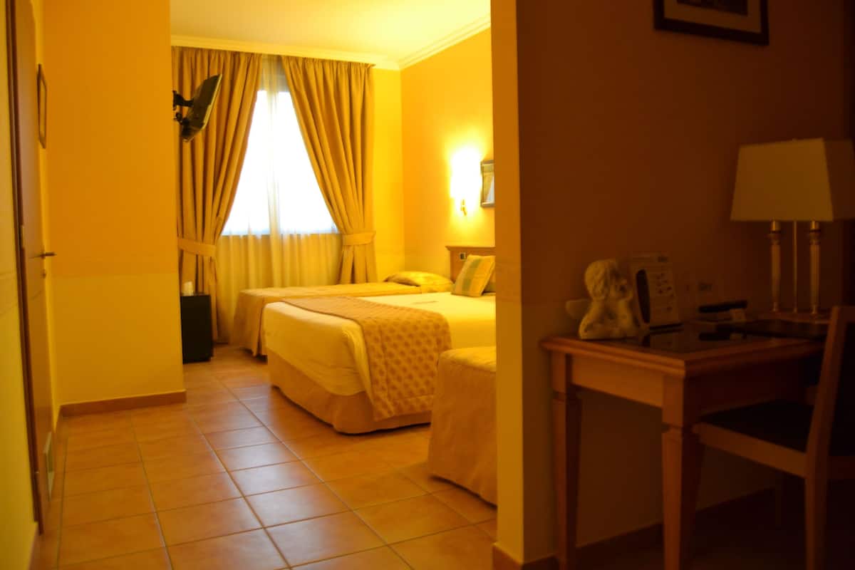 A hotel room with a bed, a desk, and a chair.