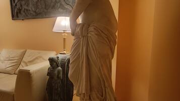 Una estatua de mármol en una habitación con un sofá beige, una lámpara y una escultura en la pared.