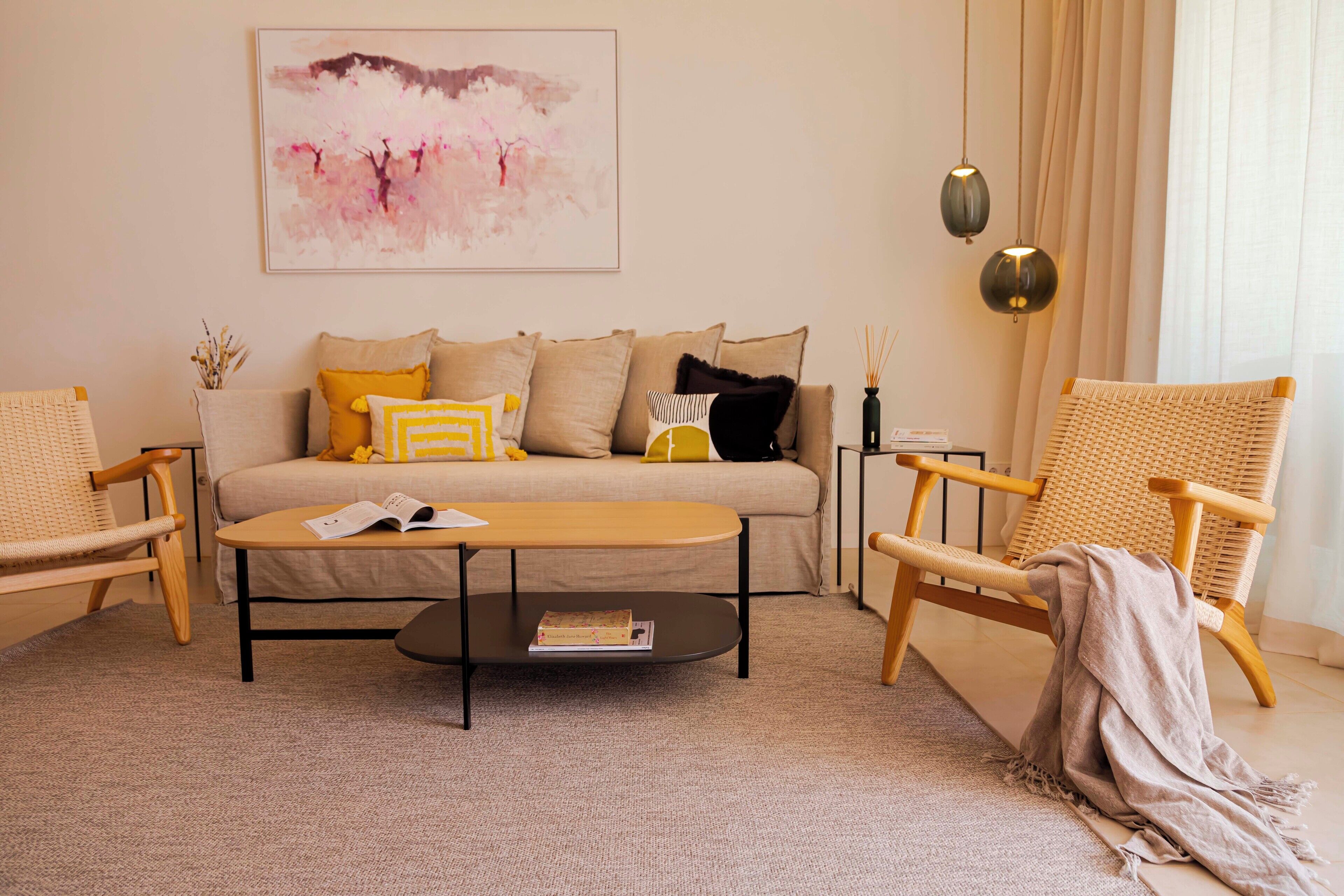 Un salon avec un canapé, deux fauteuils, une table basse et un tableau au mur.