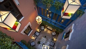 An aerial view of a courtyard with outdoor seating, a central fire pit, and hanging lanterns.
