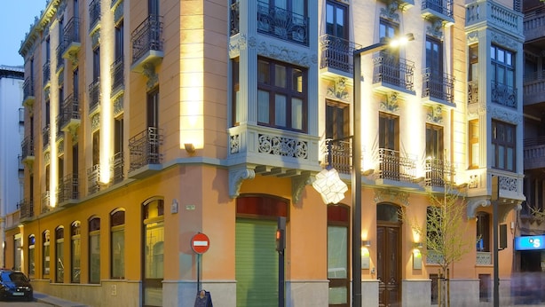 A multi-story building with ornate architectural details, including decorative balconies and a green shuttered entrance.