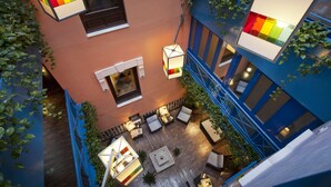 An aerial view of a courtyard with outdoor seating, a fire pit, and hanging lanterns.