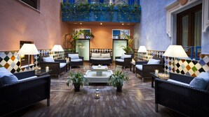 A lobby with a central seating area, two sofas, a coffee table, and potted plants.