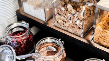 Diversos alimentos en recipientes de vidrio, incluyendo granola, cereal y un postre en capas.