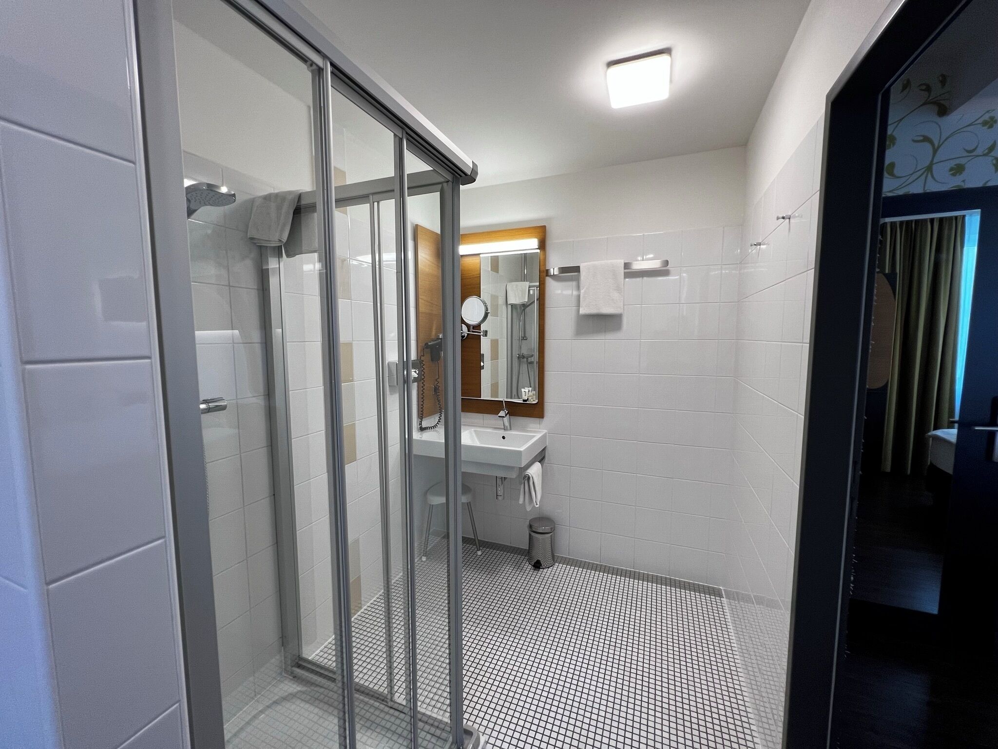 Un bagno moderno con cabina doccia in vetro, lavabo e specchio.