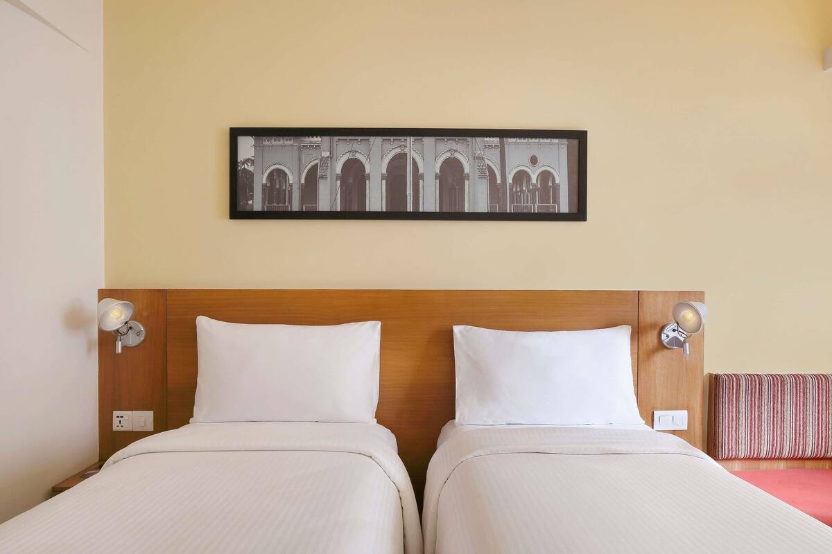 A double room with two beds, a wooden headboard, and a framed picture on the wall.
