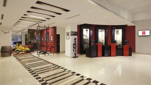 Un moderno vestíbulo de hotel con una recepción, una scooter decorativa y una alfombra estampada.