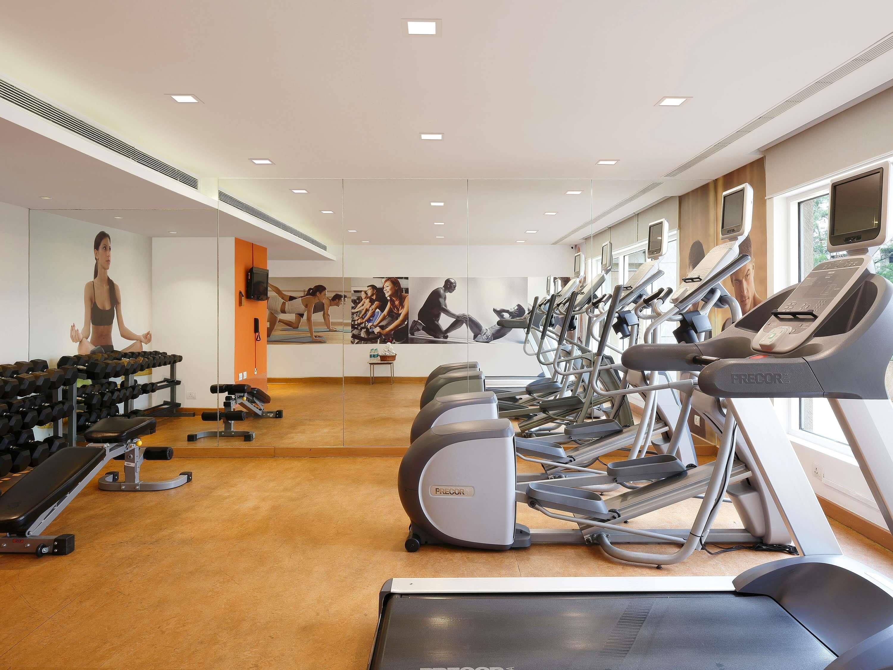 Un gimnasio con cintas de correr, mancuernas y equipo de ejercicio.