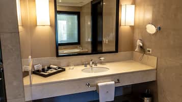 Un baño moderno con un espejo grande, un lavabo y un secador de pelo en la pared.