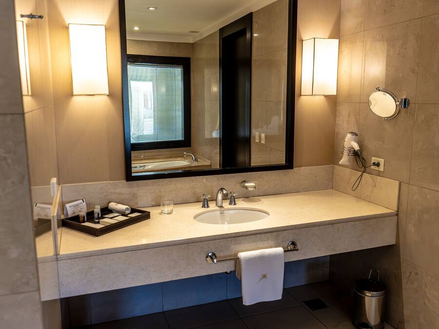 Un baño moderno con un espejo grande, un lavabo y un secador de pelo en la pared.