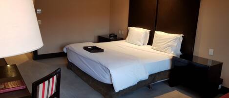 A hotel room with a bed, bedside tables, a desk, and a chair.