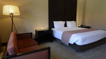 Una habitación de hotel con cama, mesita de noche, lámpara y una silla.