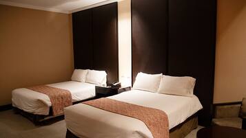 Habitación de hotel con dos camas, una mesita de noche, una silla y un espejo grande.