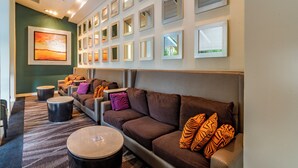 A modern lounge area with a brown sofa set, multiple round coffee tables, and a wall decorated with framed pictures.