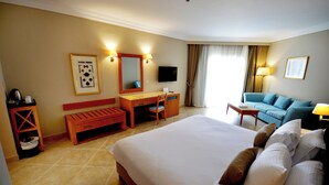 Une chambre d’hôtel avec un grand lit, un bureau, une chaise, un canapé et une télévision.