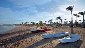 A beach with a row of palm trees, a boat, and a row of beach umbrellas. - Aurora Oriental Resort Sharm El Sheikh (Sharm El Sheikh)