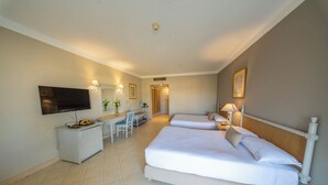 Ein Hotelzimmer mit zwei Betten, einem Schreibtisch, einem Sessel, einem Fernseher und einer Badezimmertür.