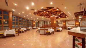 Ein geräumiges Restaurant mit mehreren Tischen und Stühlen, einer hohen Decke mit Holzbalken und großen Fenstern.