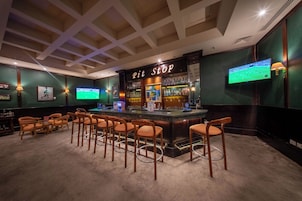 A bar area with a counter, stools, and a television screen.