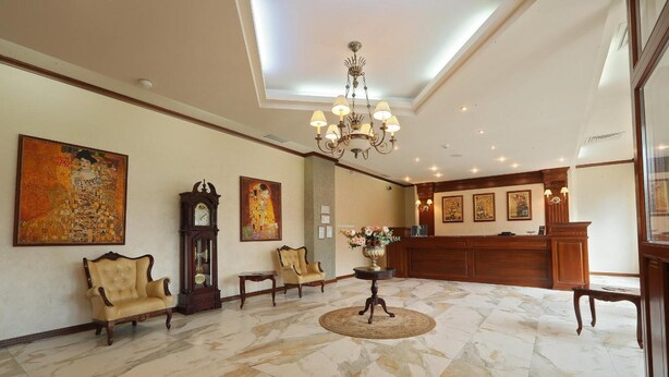 A lobby with a chandelier, a reception desk, and artwork on the walls. - Hotel Impero (Oradea)