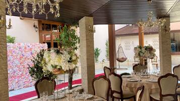 An indoor dining area with round tables, chairs, and chandeliers.