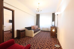 Ein Hotelzimmer mit einem Bett, einem Schreibtisch, einem Stuhl, einer Lampe und Teppichboden.