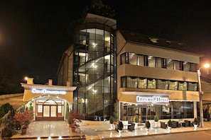 Ein Hotel mit moderner Glasfassade, einer sichtbaren Treppe und einem Sitzbereich im Freien.