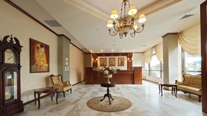 A lobby with a marble floor, a chandelier, a reception desk, and classic furniture. - Hotel Impero (Oradea)