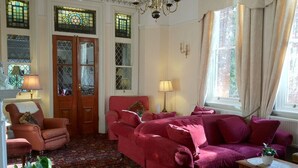 A room with a red sofa, a wooden chair, a small table, and a patterned carpet. - Ascot House (York)