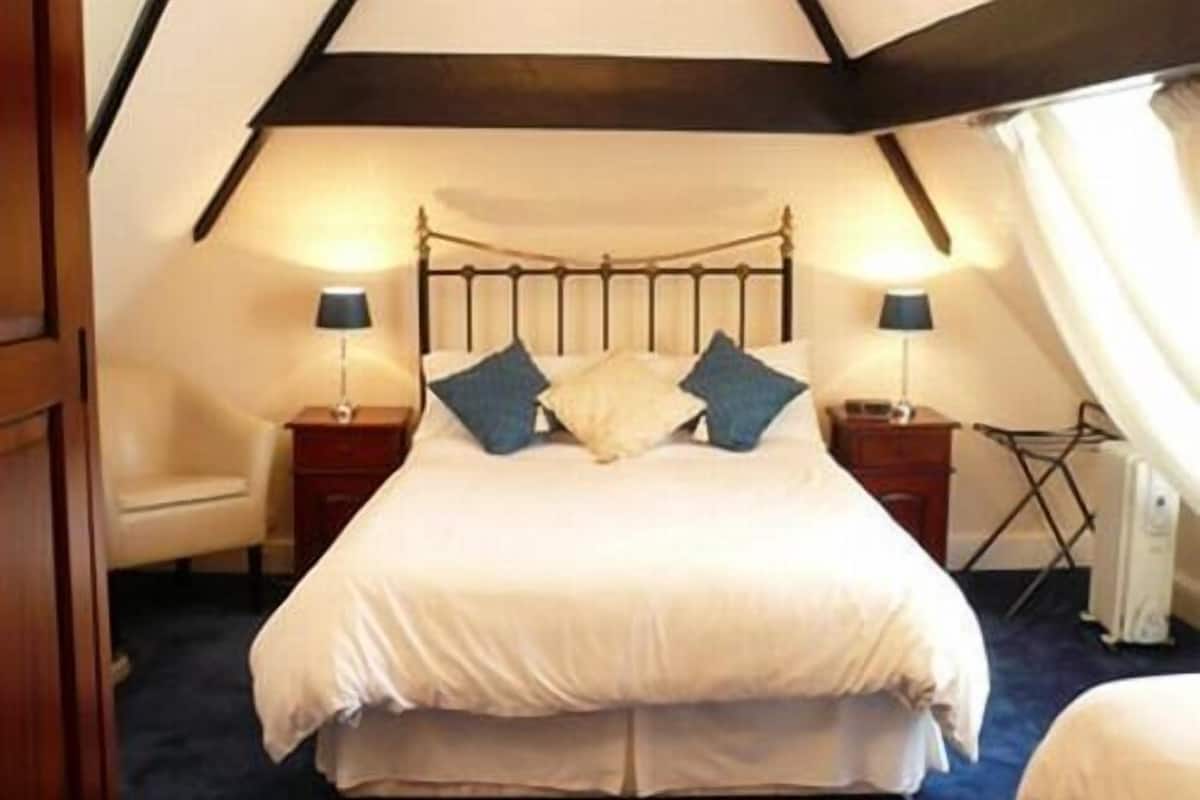 A bedroom with a bed, two bedside tables, a chair, and a radiator.