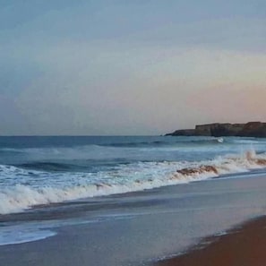 A beach with waves and a rocky outcrop in the distance. - Elmswood Guest House (South Shields)