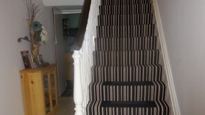 A staircase with striped carpet and white balusters.