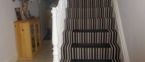 Un escalier avec une moquette à rayures et des balustrades blanches.