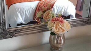 A hotel room with a bed, a nightstand, a lamp, and a vase with flowers.
