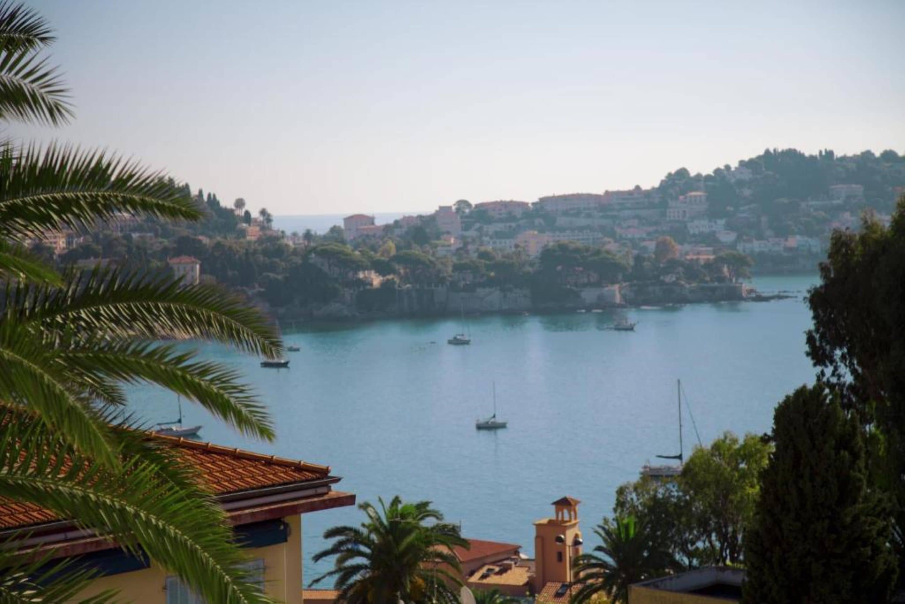 Una località balneare con edifici su una collina che si affaccia su una tranquilla baia con imbarcazioni.