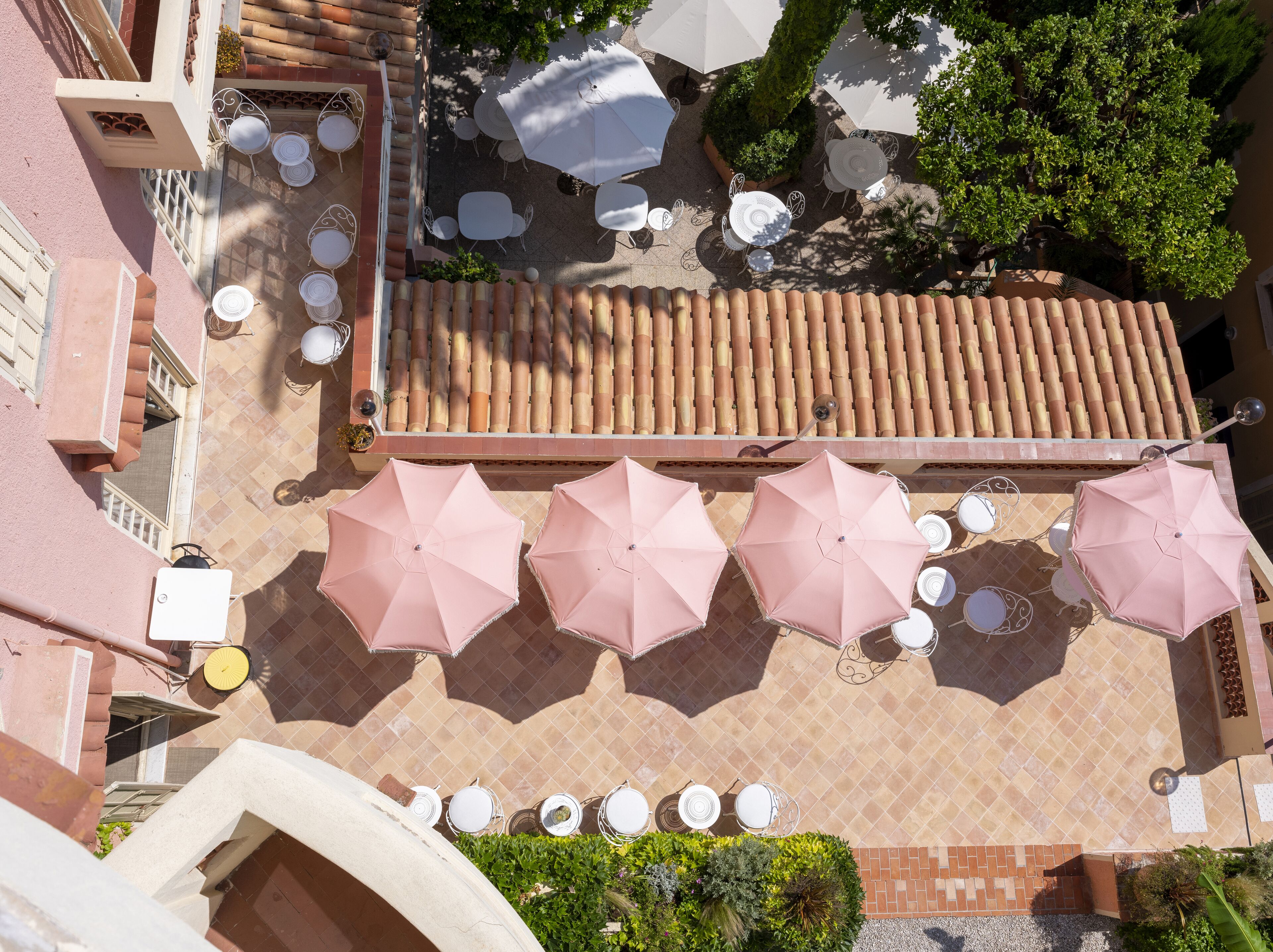 An outdoor patio area with multiple tables and chairs, surrounded by large umbrellas.