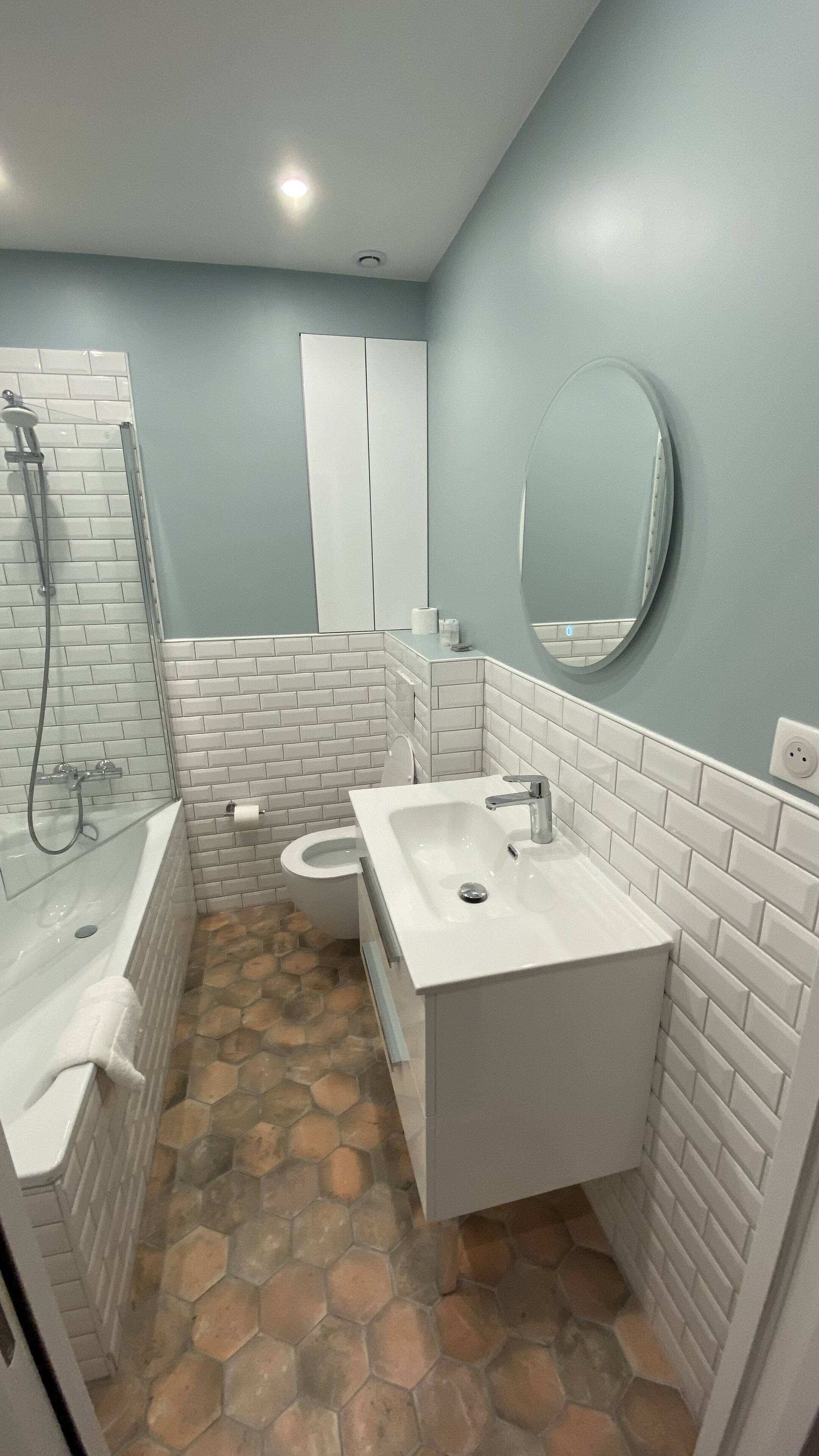 Une salle de bain équipée d’une douche, de toilettes, d’un lavabo et d’un miroir au mur.