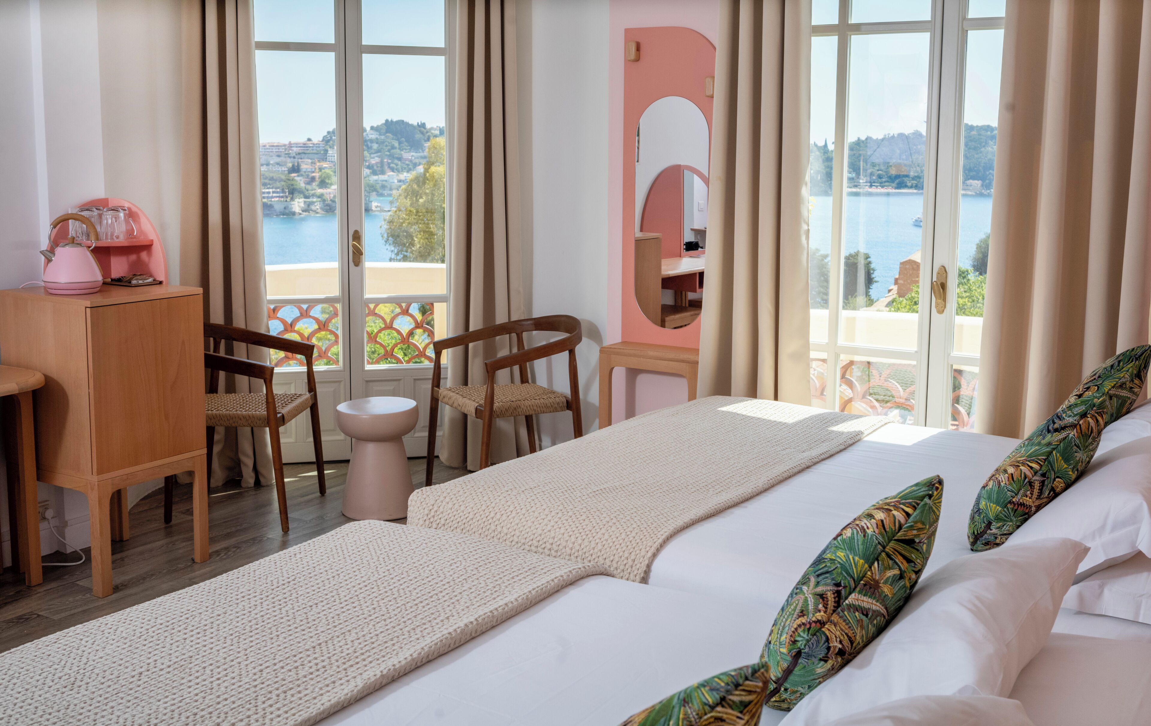 Una camera d'albergo con un letto, due poltrone, un tavolino e vista su un lago.