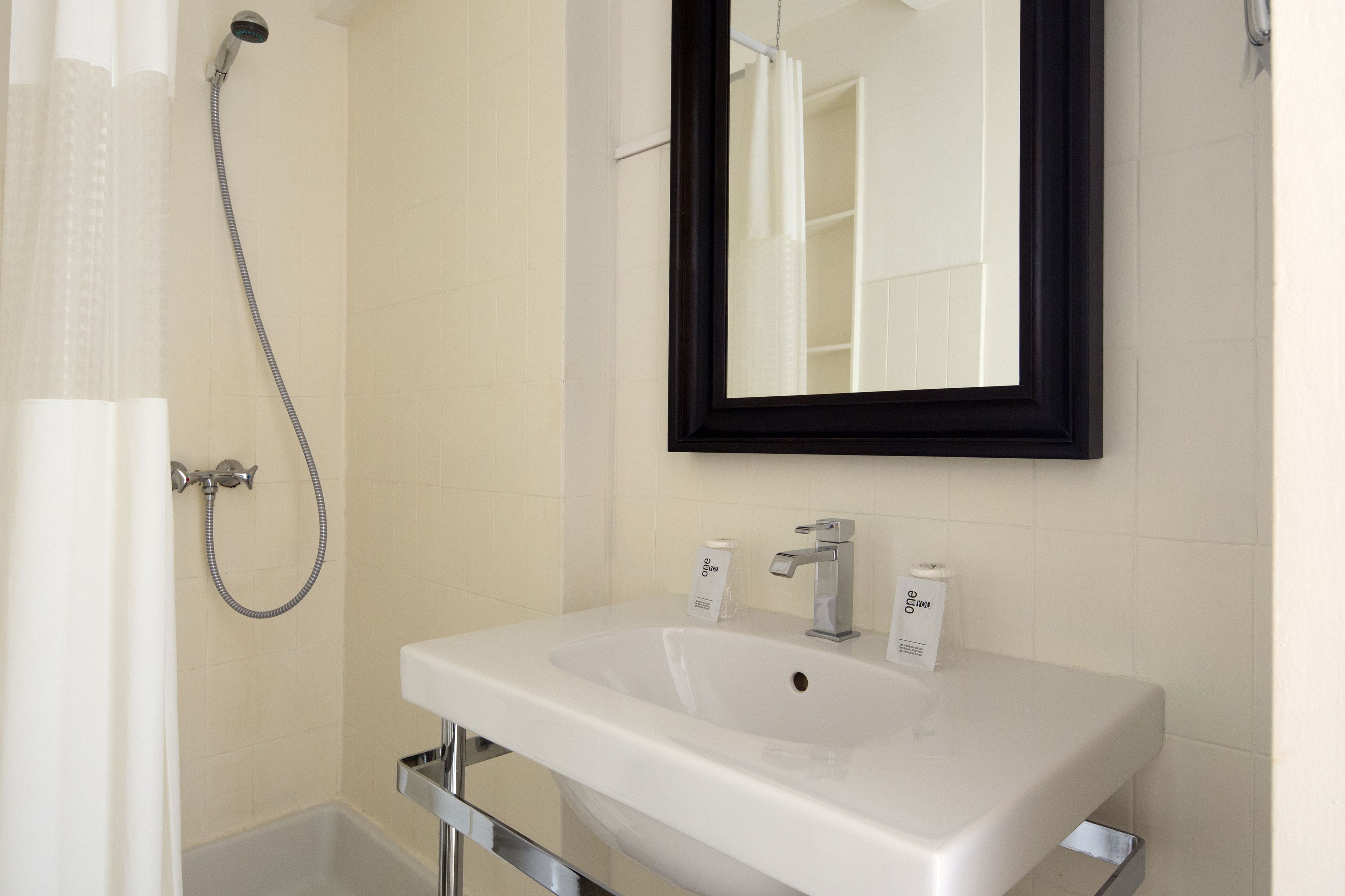 A bathroom with a white sink, a mirror, and a shower.