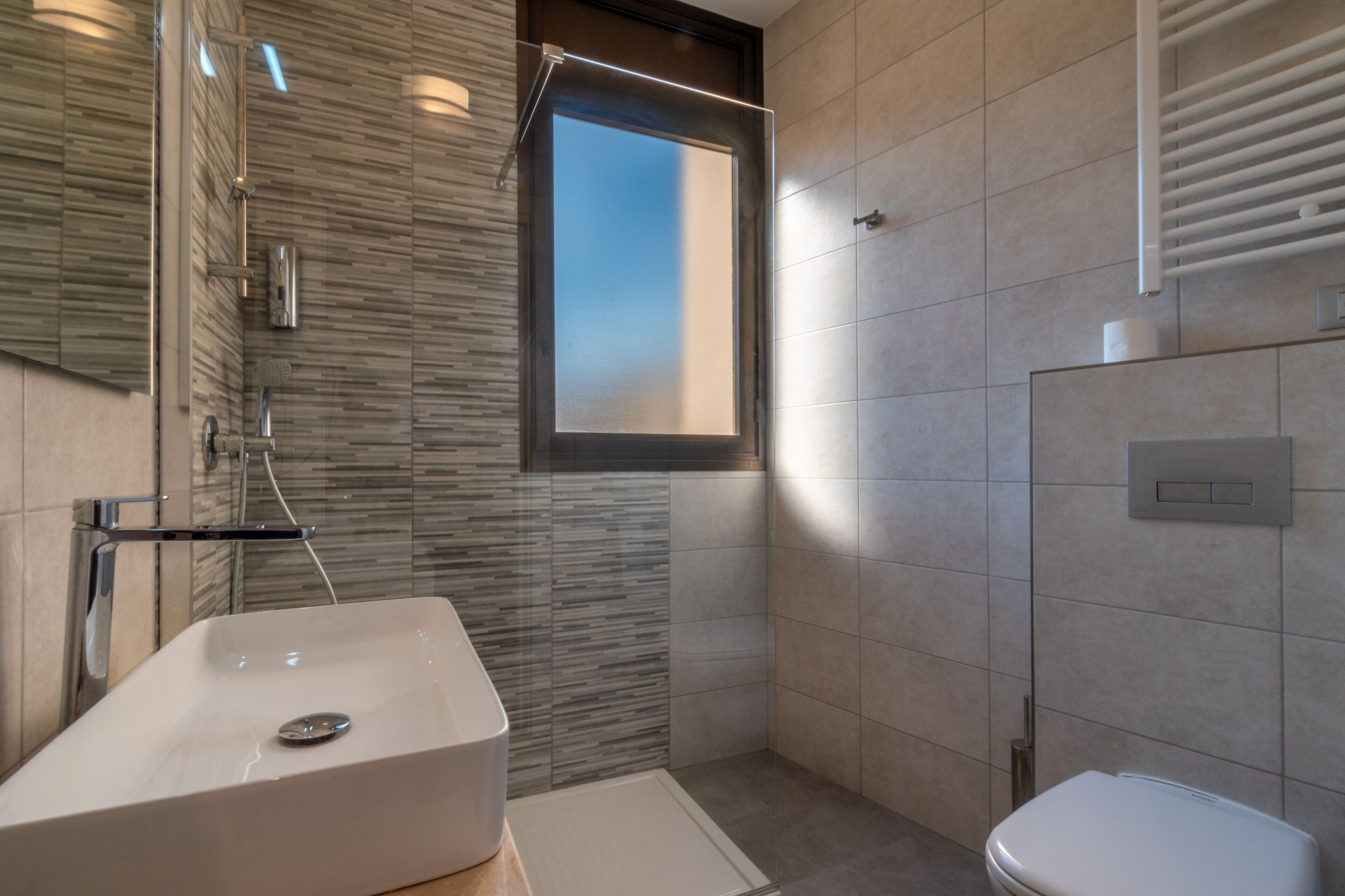 A modern bathroom with a rectangular sink, a shower, and a toilet.