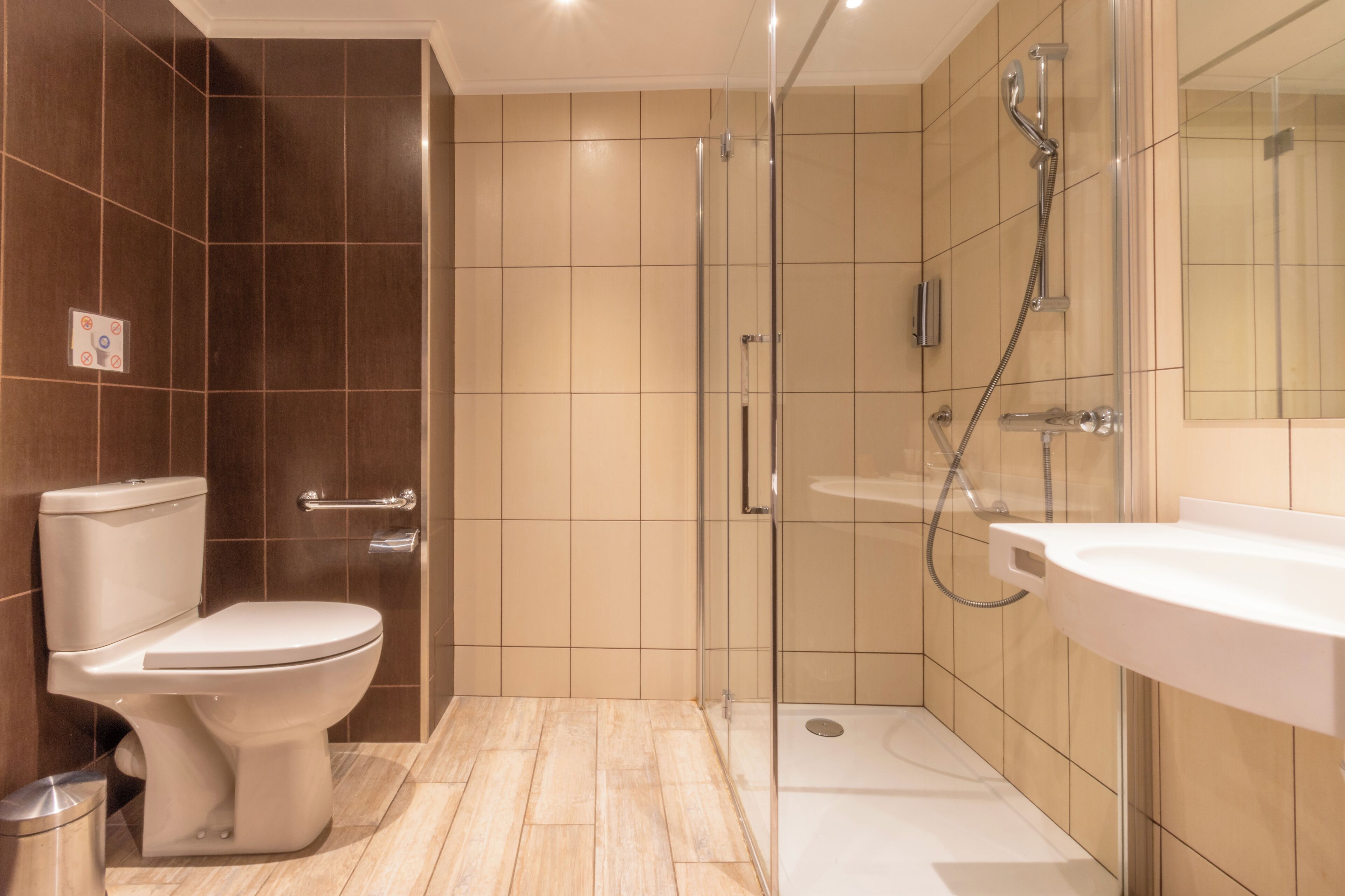 Et moderne badeværelse med toilet, glas brusekabine og vask.